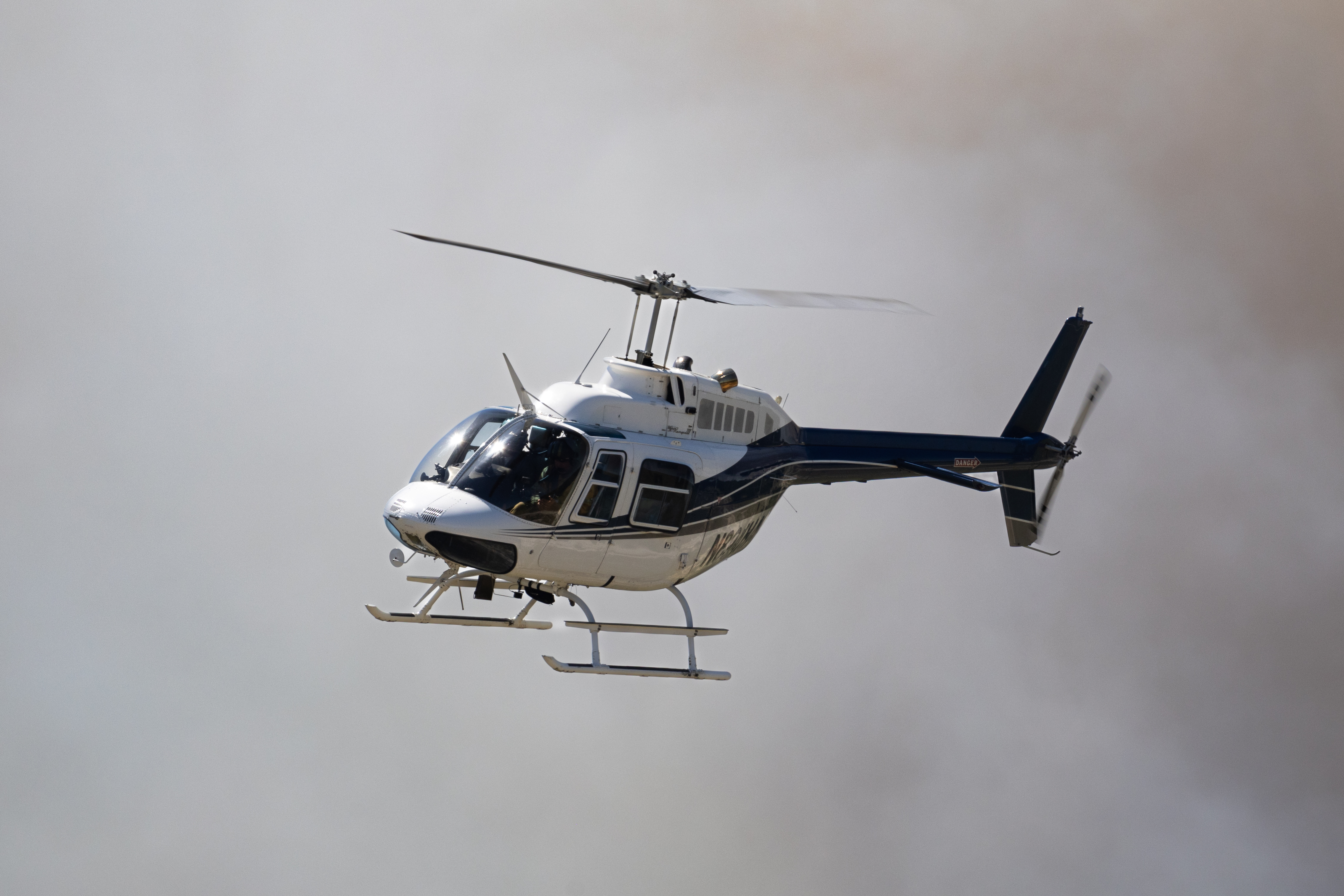 A helicopter flies through gray smoke.