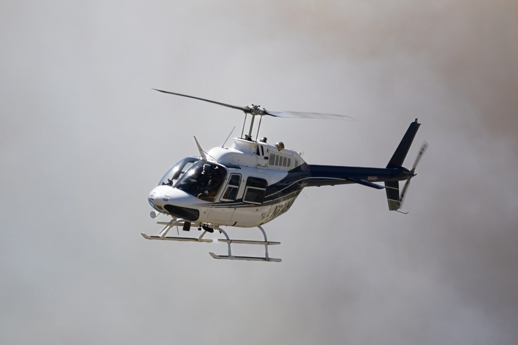 A helicopter flies through gray smoke.