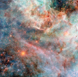 Part of a nebula in space. Layers of gas and dust clouds in different colors, from blue and green shades to pink, red, and black, each indicating light emitted by different molecules, comprise the nebula. The background cloud layers are thicker and puffier, though still translucent, and the upper layers are thin and bright at the edges. Behind the clouds are many small, mostly orange and some blue, stars.