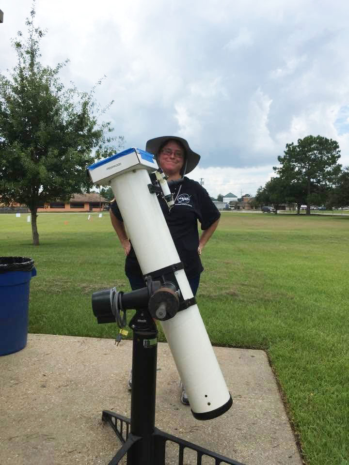 Christina Zeringue is seen standing behind a telescope outdoors