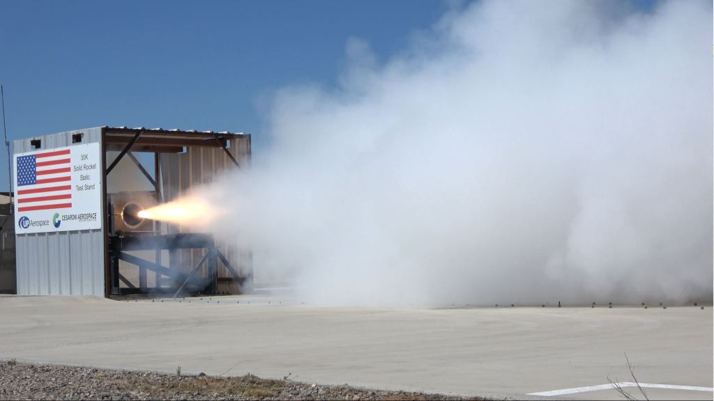 Flames an smoke are shooting out of a rocket engine while it is being tested.