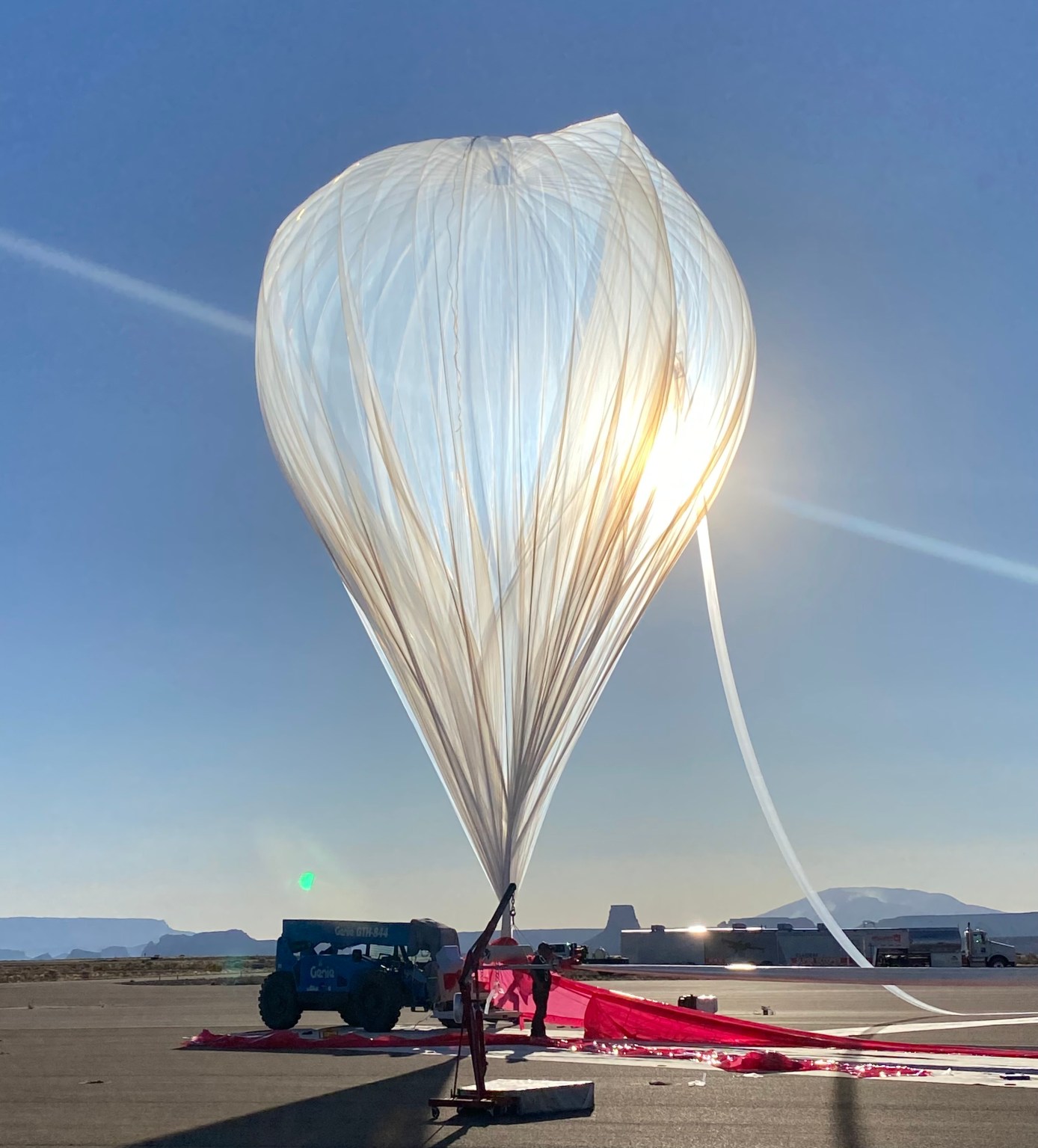 A large high-altitude balloon sits inflated against a blue sky.
