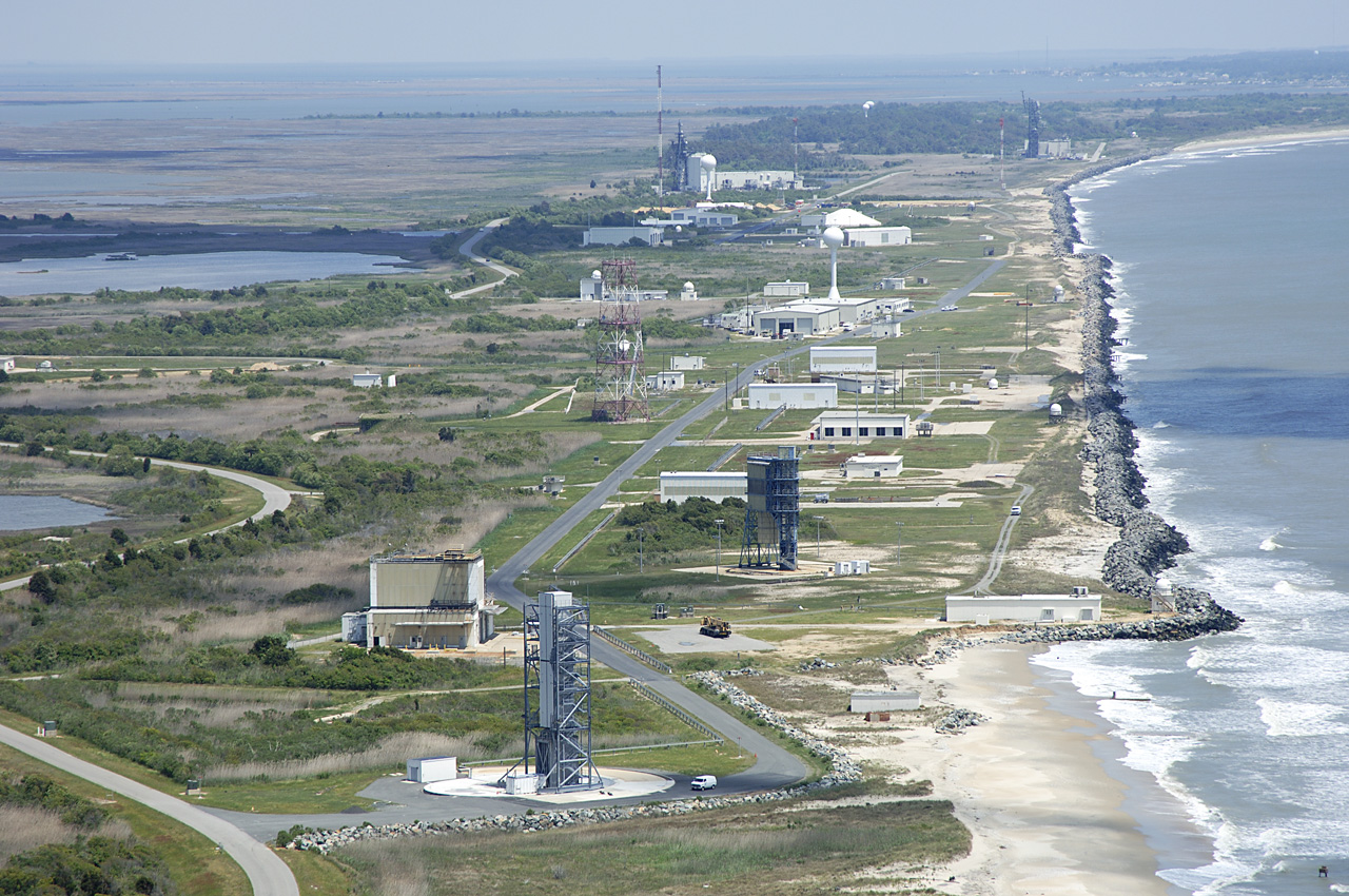 An image showing the Wallops Research Range. It depicts several buildings, towers, and launchpads on a beach next to the ocean