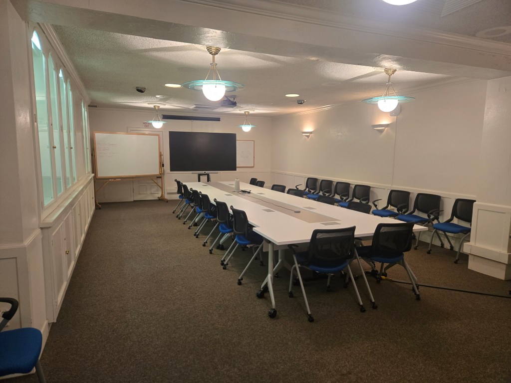 Macon Meeting room shown in default furniture configuration of boardroom style table configuration with 14 chairs at the table, as well as an additional 10 for overflow seating.