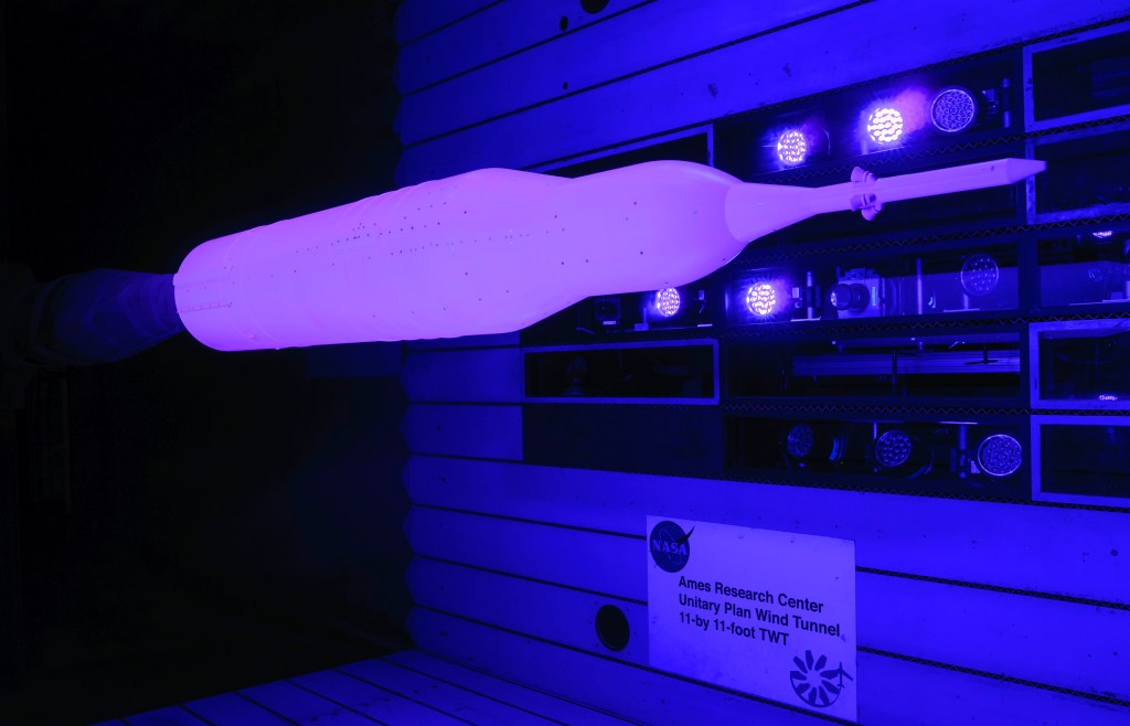 A rocket glows pink from the use of Pressure Sensitive Paint inside a NASA wind tunnel.