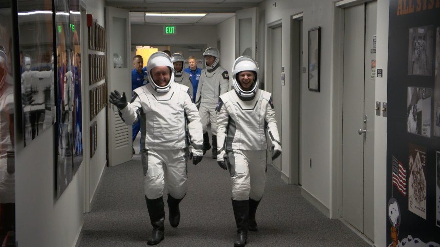 Astronauts walking down hall.