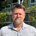 Portrait photo of NASA Ames Earth Scientist Matthew Fladeland, standing outside in front of a building.