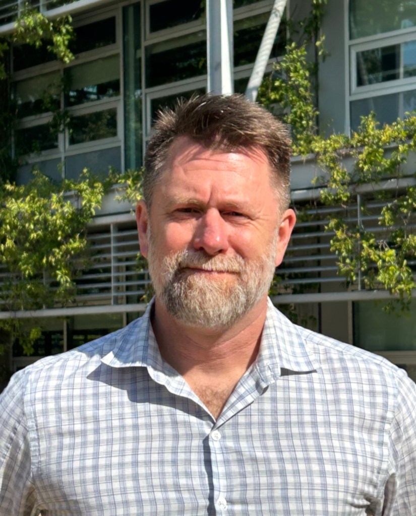 Portrait photo of NASA Ames Earth Scientist Matthew Fladeland, standing outside in front of a building.