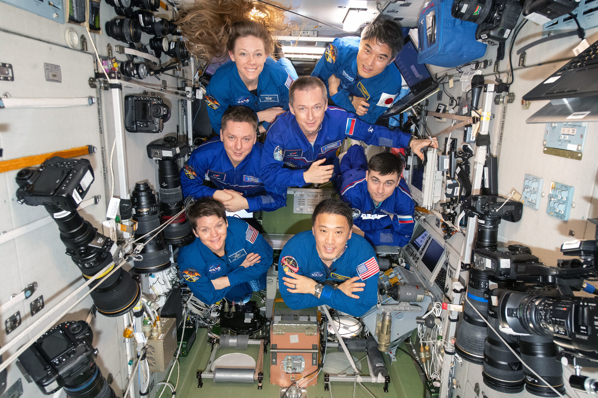 The seven-member Expedition 73 crew poses for a portrait inside the International Space Station's Zvezda service module.