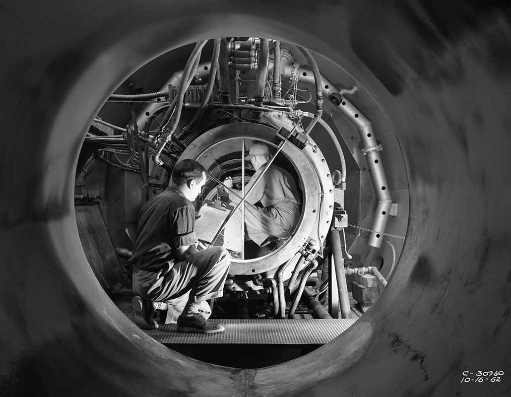 View through test cellof man looking at engine.