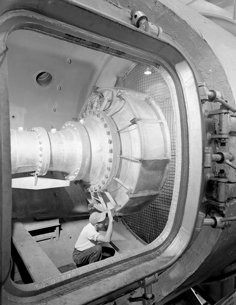 Man in test cell looking at hardware.