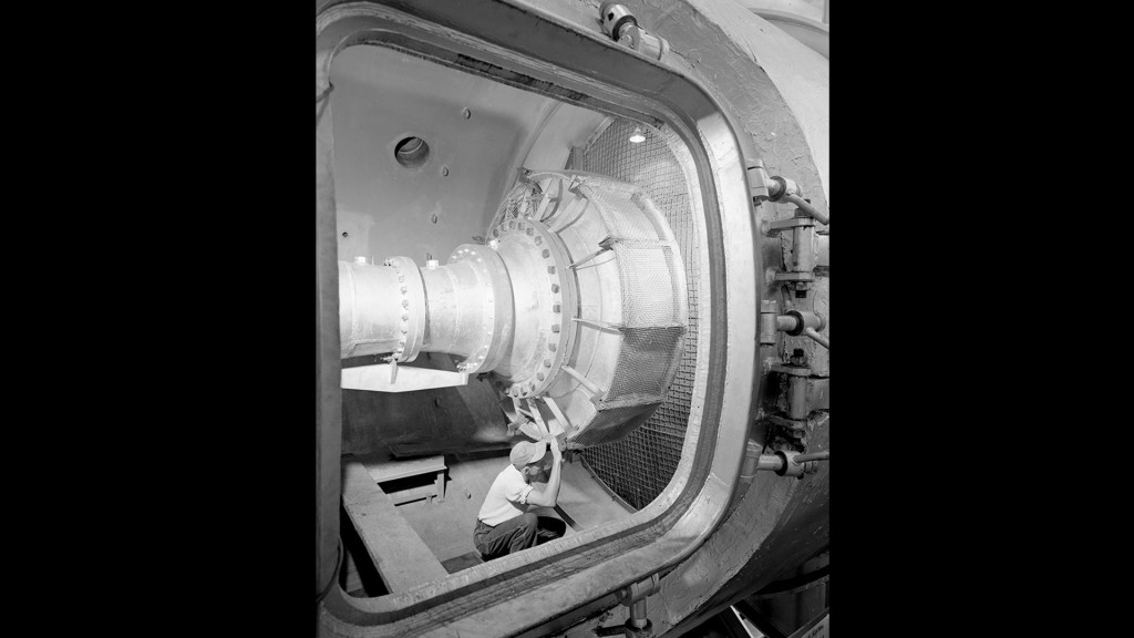 Man in test cell looking at hardware.