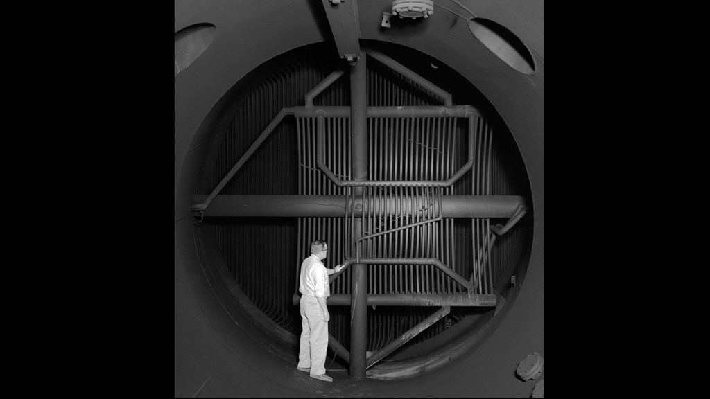 Man inspecting interior of cooling equipment.