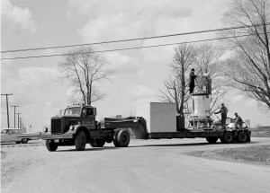 Truck pulls trailer bed with Kiwi engine on it.