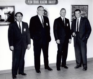 Four men standing in facility.