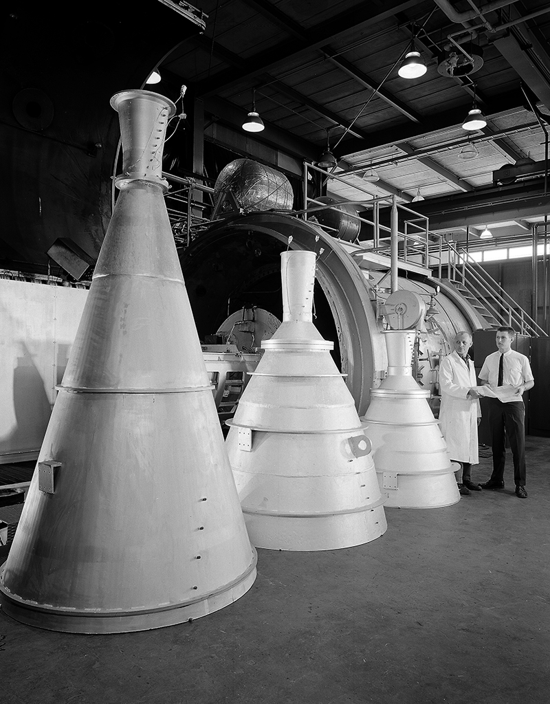Three large rocket nozzles standing on floor.