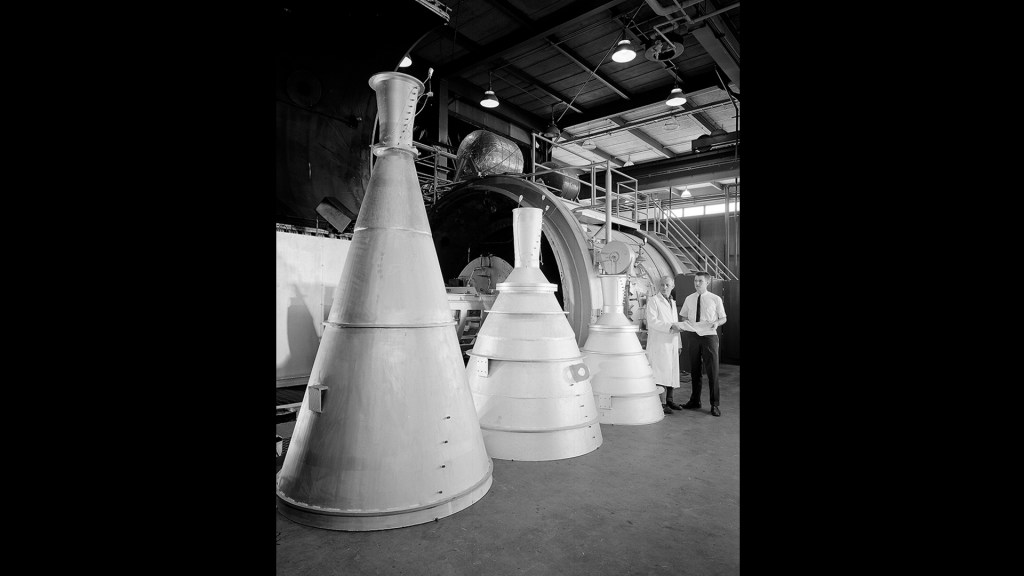 Three large rocket nozzles standing on floor.