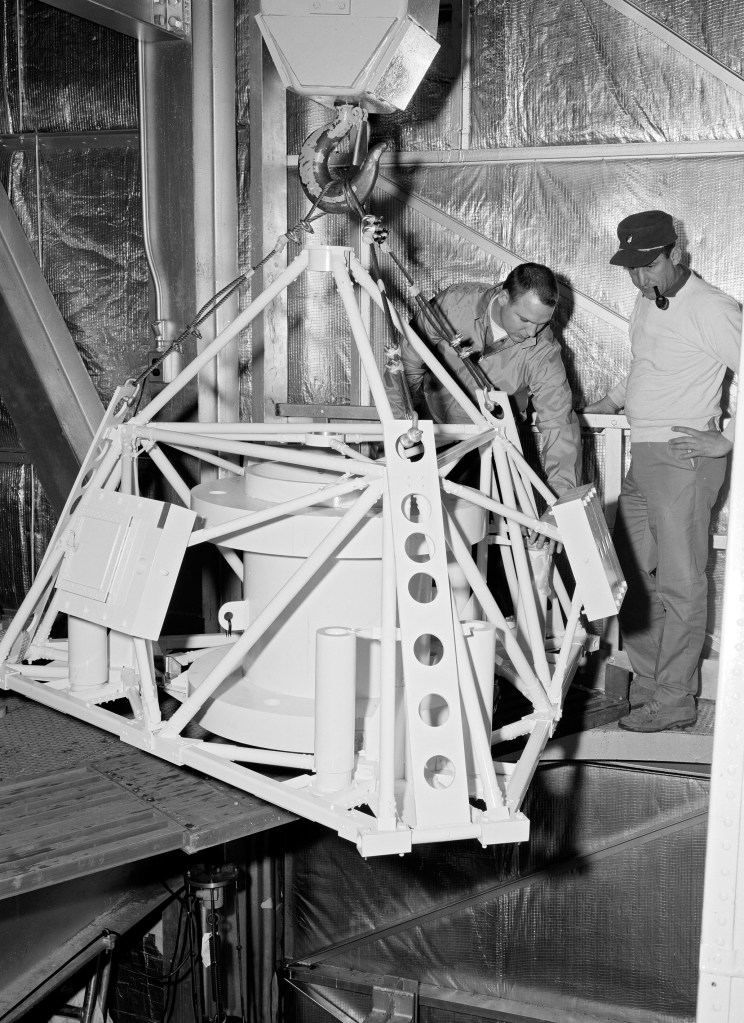 Mechanics install a replica of the Surveyor spacecraft to the Atlas-Centaur rocket in E Stand