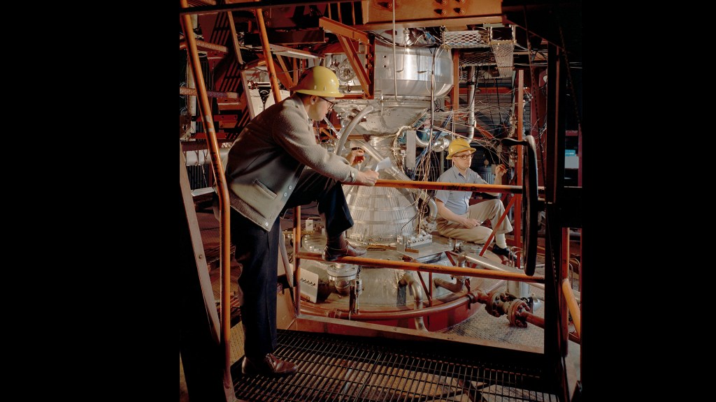 Two engineers examine Kiwi engine in B-1 stand
