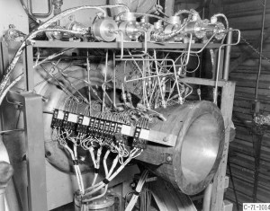 A technician inspects an experimental copper nozzle at the J-1 test rig