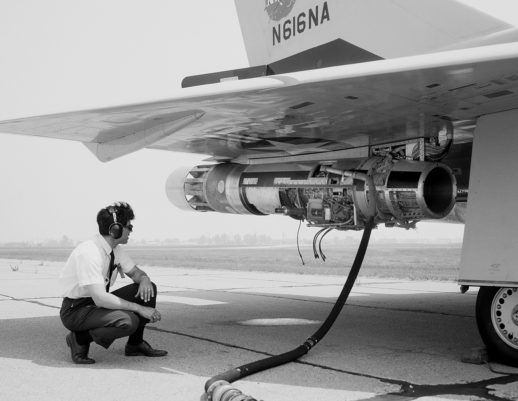 Man squatting to view engine under wing.