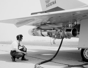 Man squatting to view engine under wing.