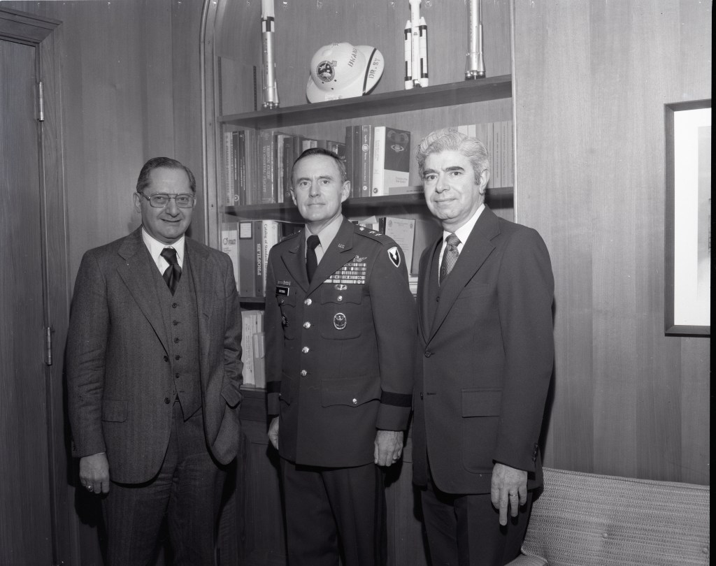 Three men standing in office.