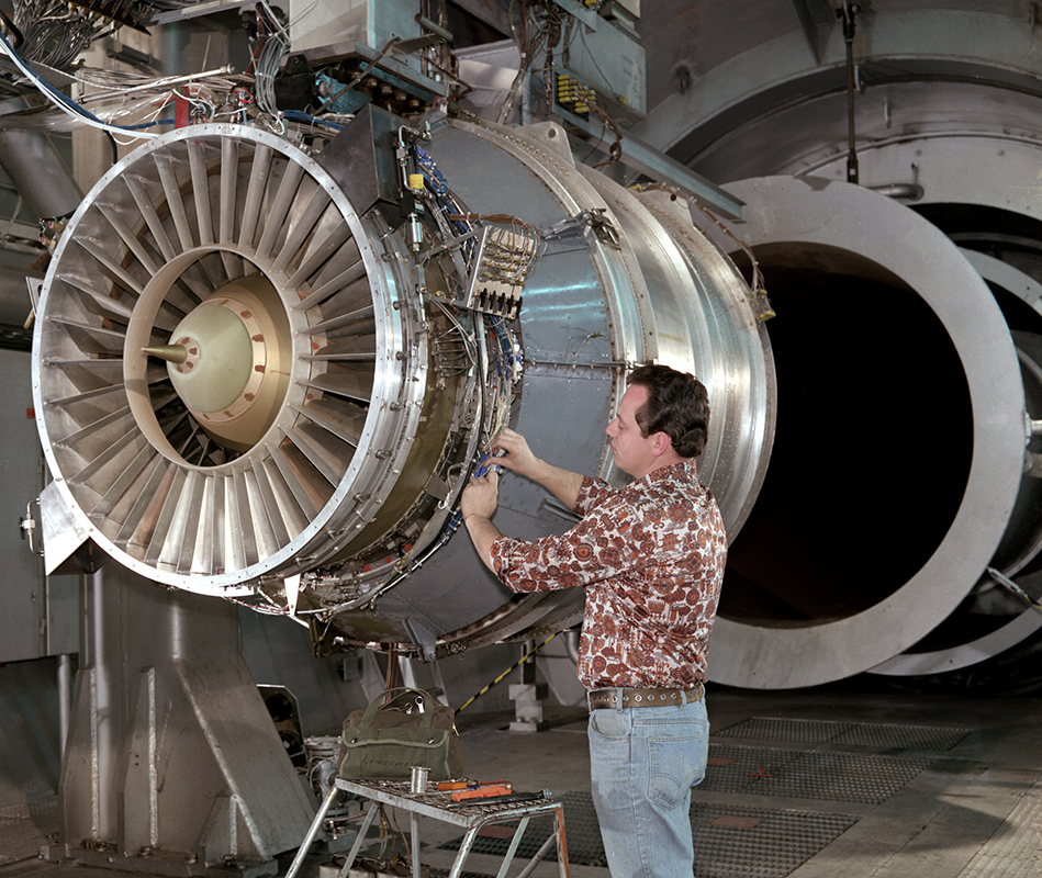 A technician installs instrumentation on engine