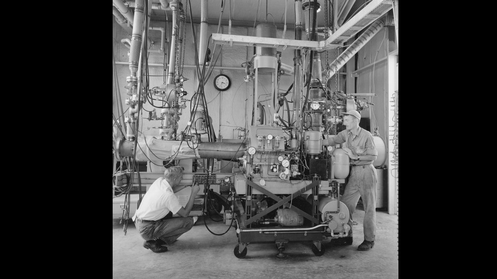 Two mechanics prepare a test rig