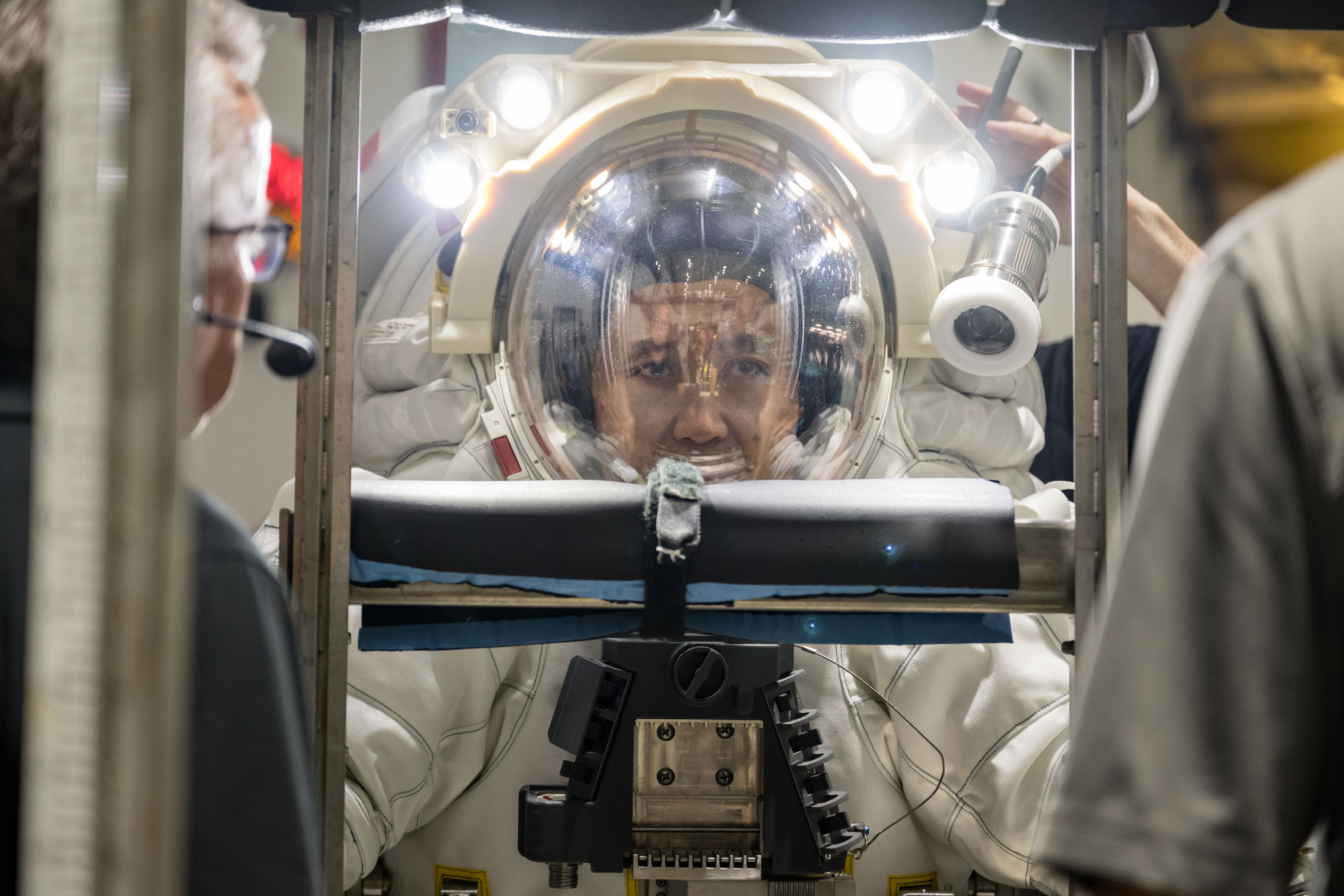A closeup shot of Axiom Space astronaut and Chief Technology Officer Koichi Wakata wearing a white spacesuit while attached to a metal donning stan...