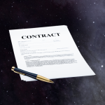 A pen and a white sheet of paper that says, Contract.