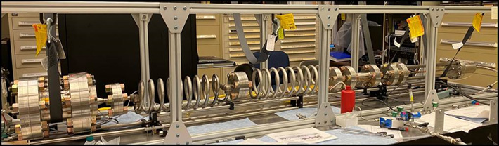 A long laboratory testbed with coiled metal tubing and components mounted on a frame, which is part of the TREES thermal management system.