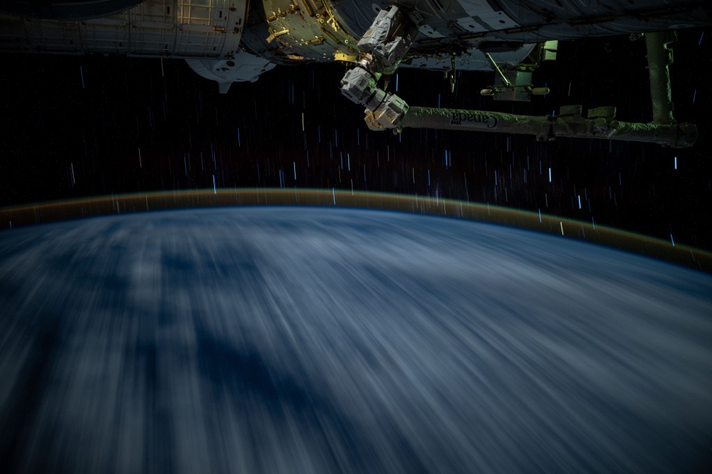 In this long duration photograph taken from the International Space Station clouds streak across the Indian Ocean, a dim atmospheric glow crowns Earth's horizon, and stars trail above the planet's horizon. The orbital outpost was soaring 261 miles above the Indian Ocean southwest of Indonesia at approximately 3:14 a.m. local time