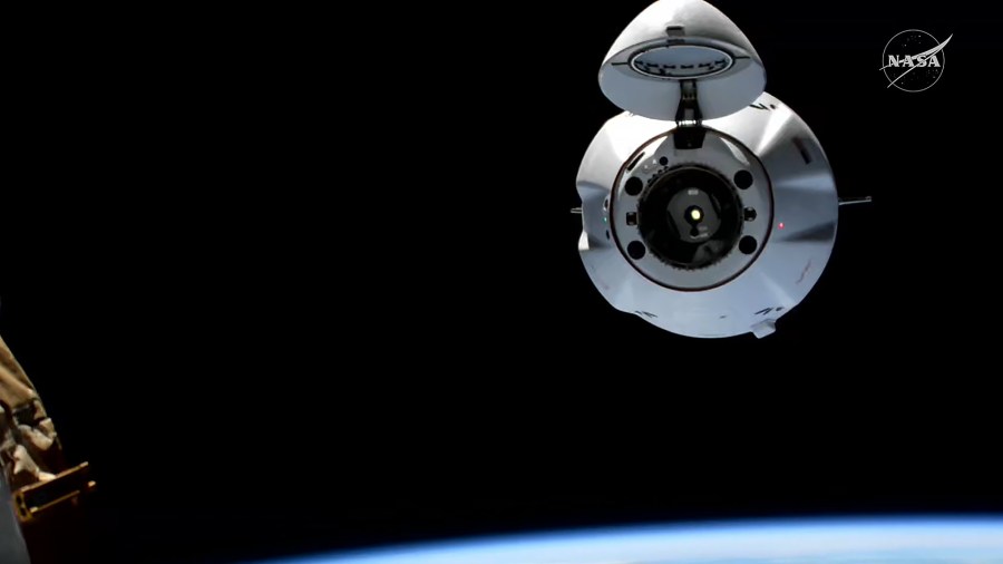 The SpaceX Dragon cargo spacecraft, with its nosecone open, approaches the International Space Station for an automated docking.