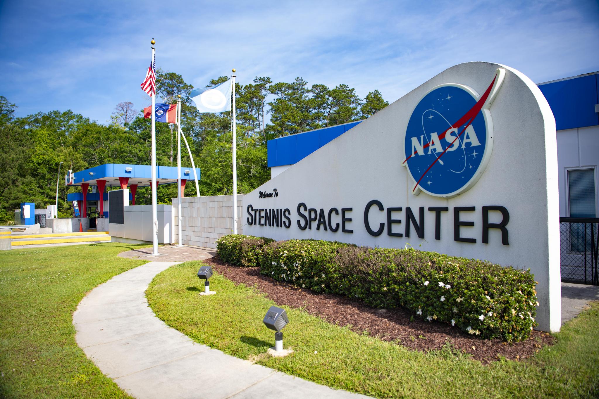 a view of the South Gate at Stennis Space Center is captured with the American, state and NASA flags flying and the guard shed in the background