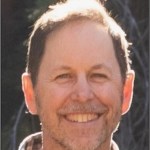 Headshot of a man with short borwn hair and scruff.
