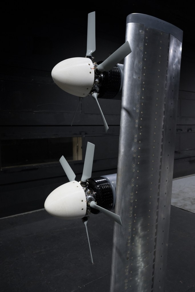 Close-up view of two propellers mounted on a vertical metal structure in a testing facility.