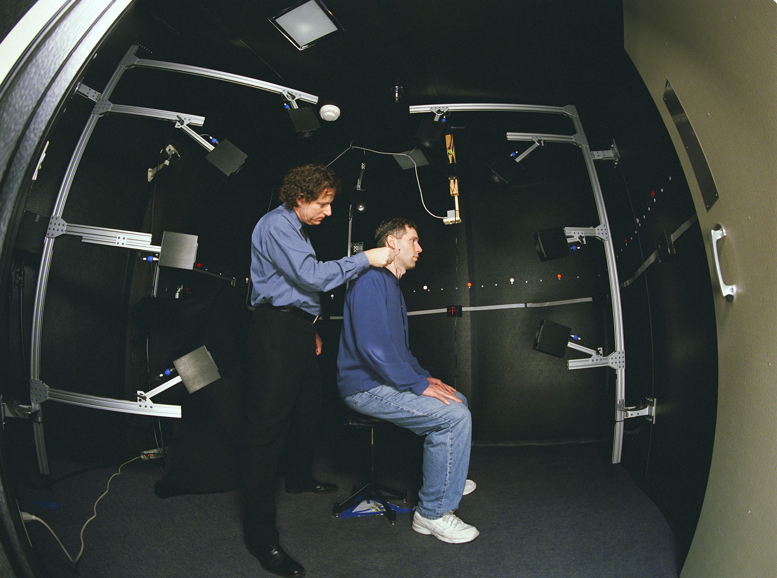 Image of NASA researcher Durand Begault in the 3D Audio Lab prepping a test subject for a Spatial Audio study.