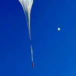 Two NASA scientific balloons floating in a clear blue sky over New Mexico, with the CDCP balloon in the foreground and JPL-REMOTE balloon visible in the distance.