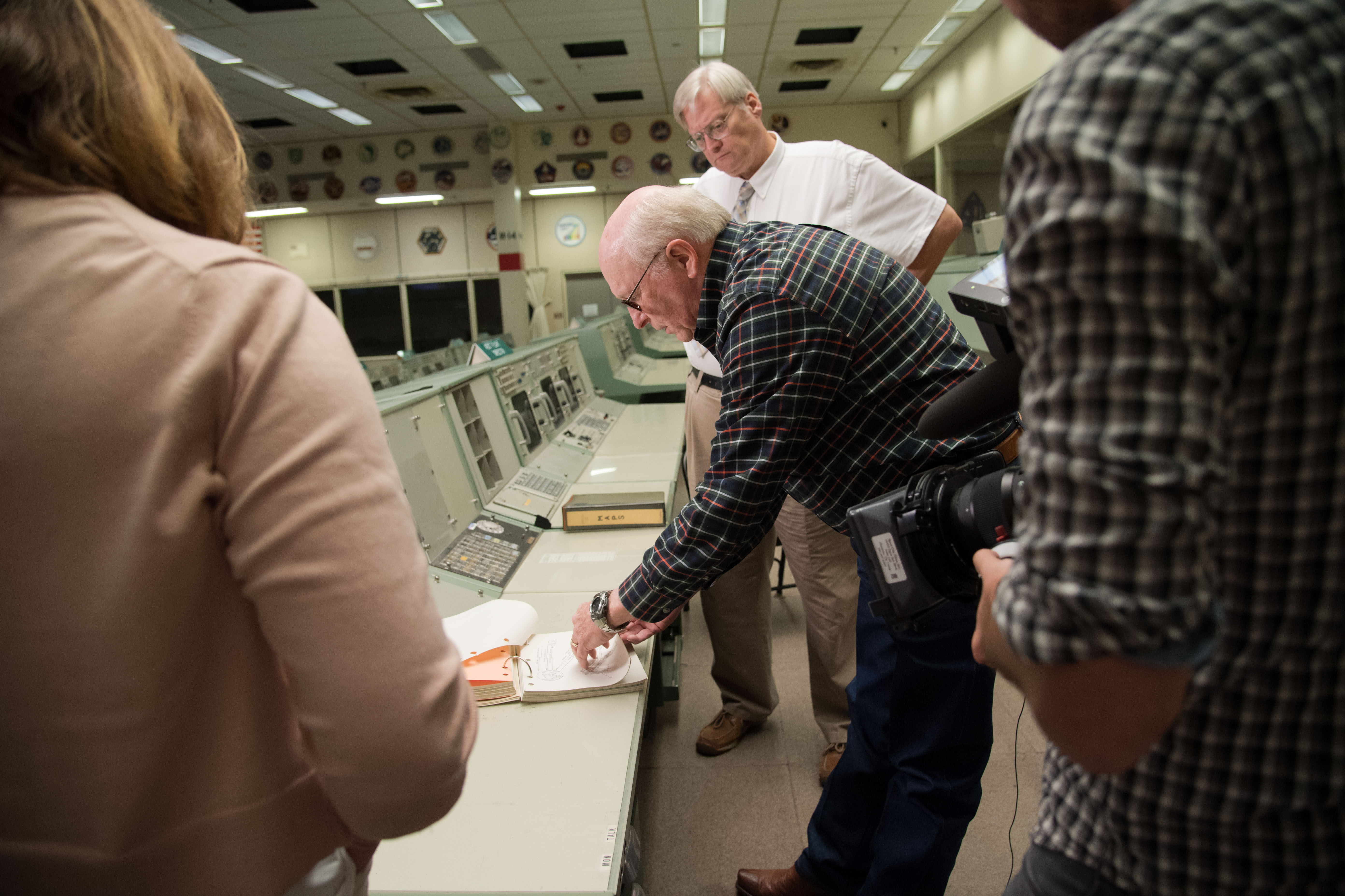 Former Apollo Flight Controller James Covington standing in front of his position in Mission Control during Apollo