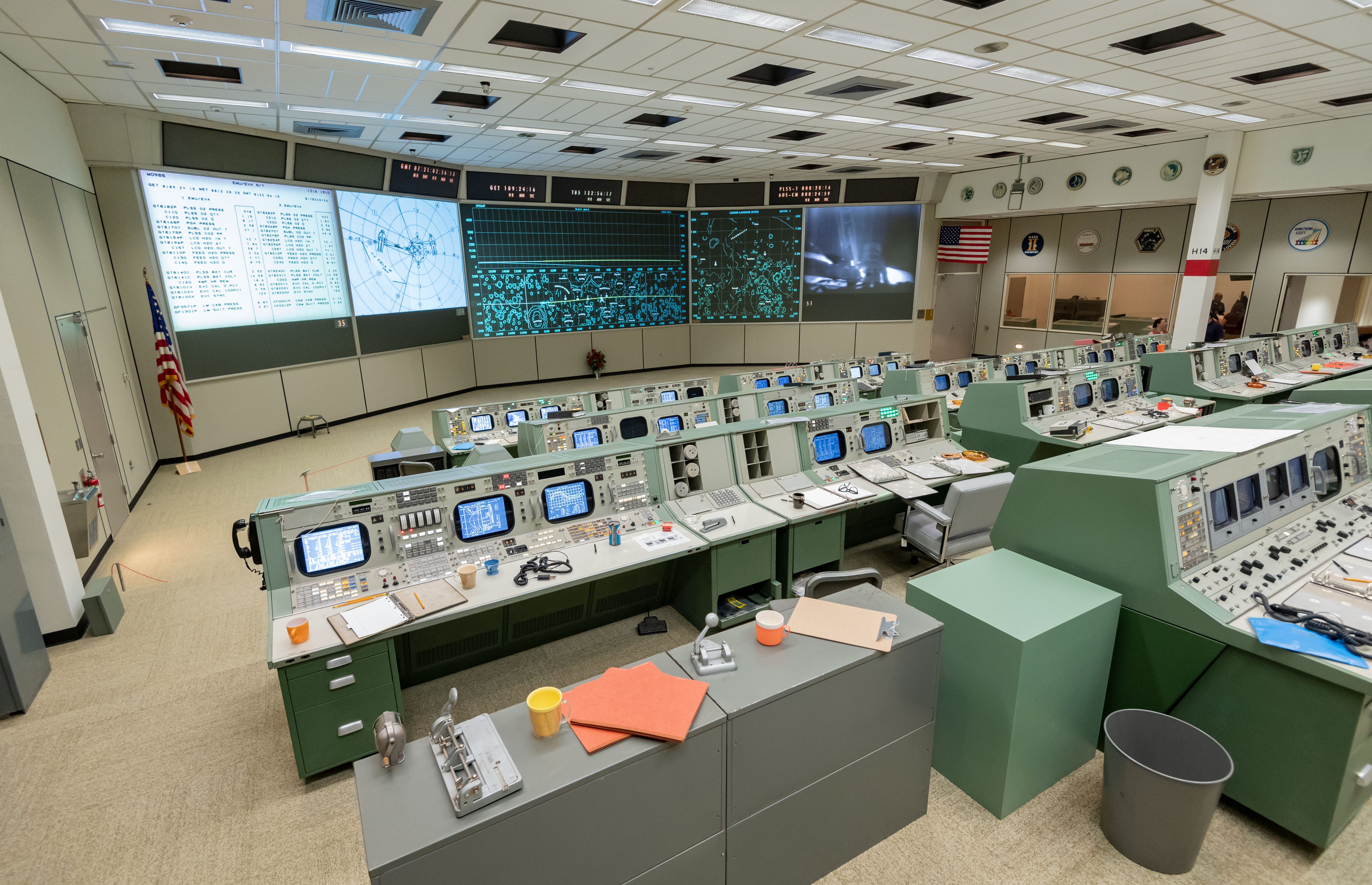Consoles with documents and personal items and views of the front displays in restored Apollo MOCR in its final configuration.