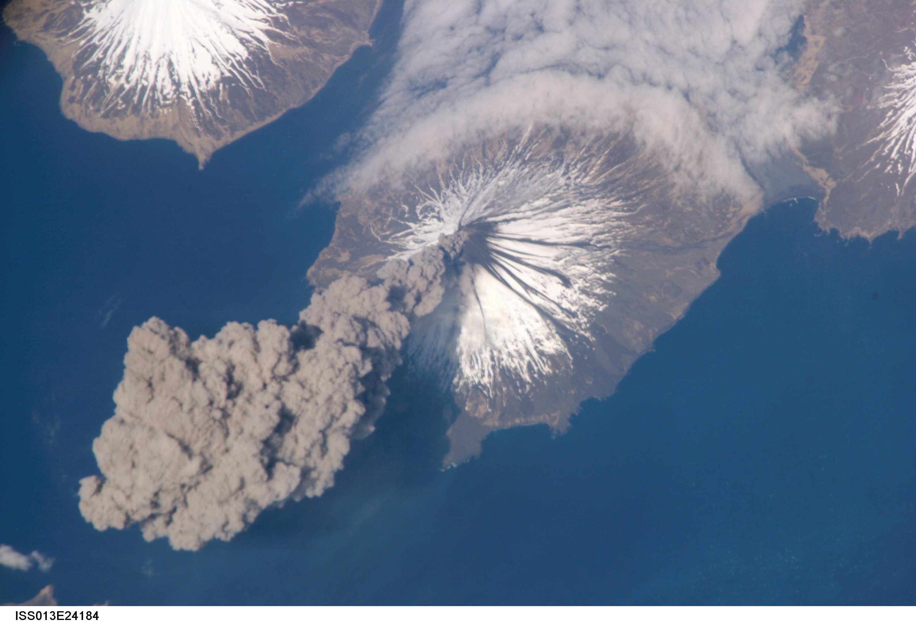 A volcanic eruption on Earth is seen in this picture taken by a space station crew member. Dark grey clouds of ash and smoke are seen coming out of the volcano.