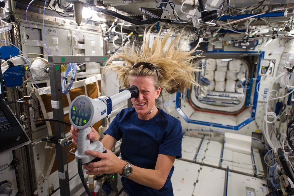 Astronaut Karen Nyberg is seen floating in the space station. Karen is looking into a device to measure ocular health.
