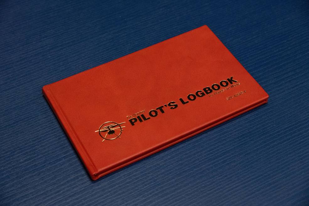 A red Pilot's logbook on a blue background.