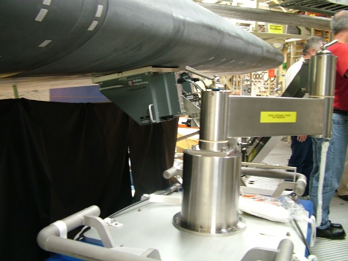 Photograph of the manipulator system and the “right angle” hood/camera assembly performing an inspection in the OPF at KSC on the Space Shuttle Discovery following STS-114.
