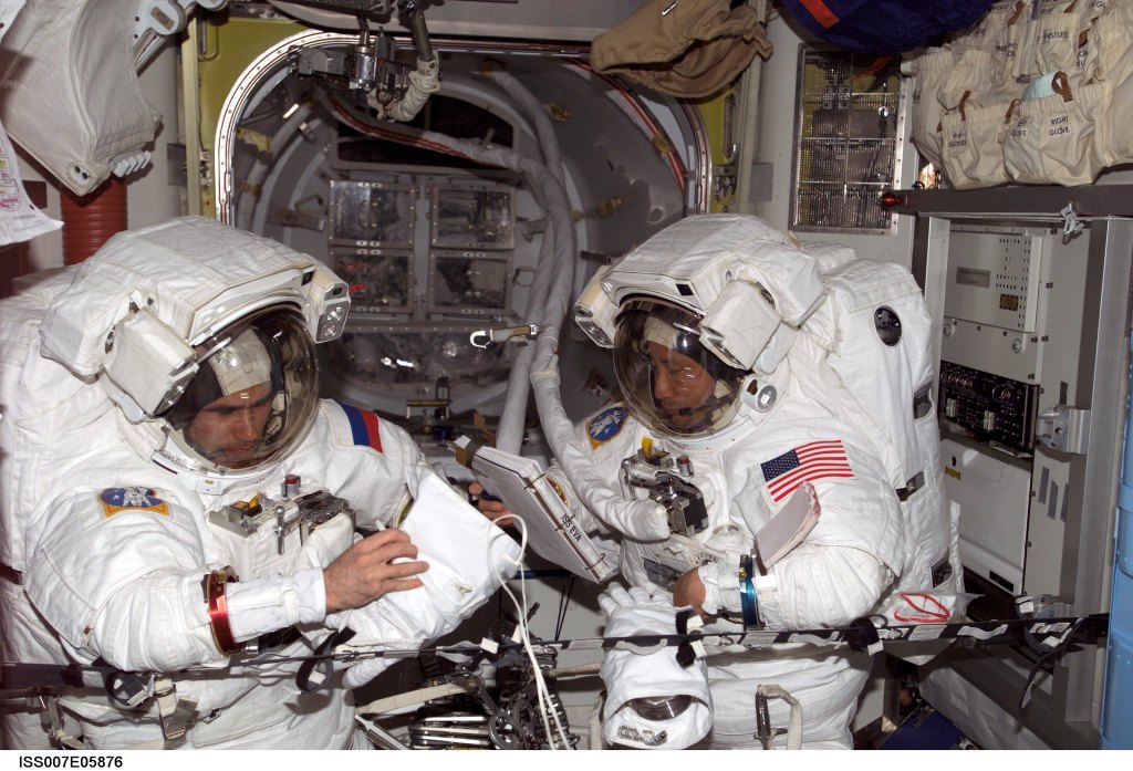 On the left, Cosmonaut Yuri I. Malenchenko and on the right NASA astronaut Edward T. Lu, are seen wearing spacesuits while performing an Extravehicular Mobility Unit spacesuit fit check.