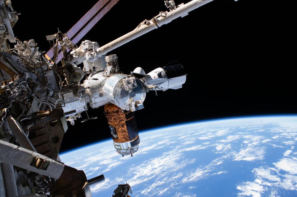 The SpaceX Crew Dragon, the Japanese H-II Transfer Vehicle-9 resupply ship, and Europe’s Columbus laboratory module figure are attached to the U.S. Harmony module to the left, with the International Docking Adapter on top. The Earth is the midground and the blackness of space is in the background.