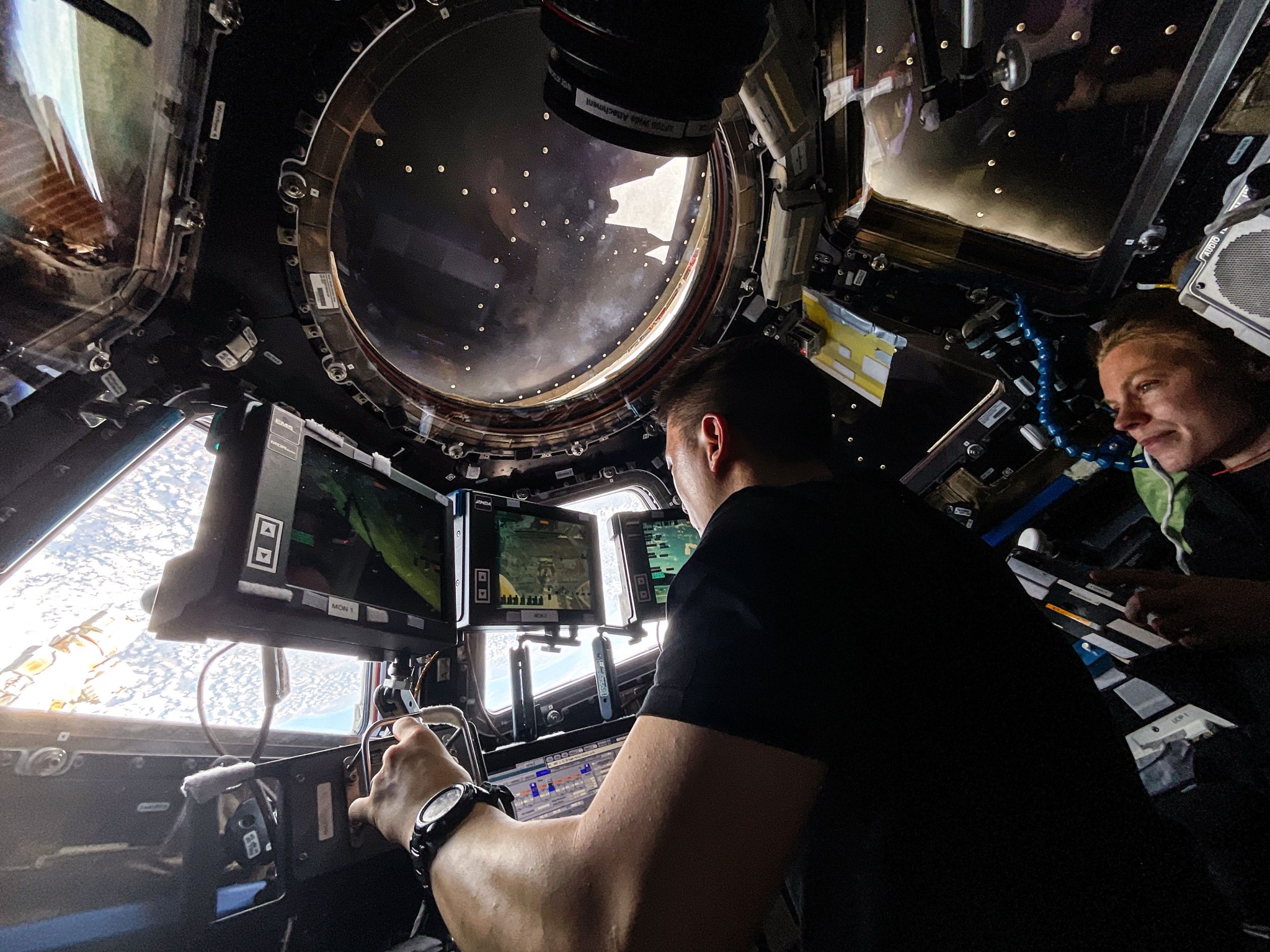 Expedition 73 Flight Engineers Jonny Kim and Zena Cardman, both NASA astronauts, practice Canadarm2 robotic maneuvers at the robotics workstation inside the International Space Station's cupola. The duo was preparing for the robotic capture of the Northrop Grumman Cygnus XL cargo spacecraft that launched on Sept. 14, 2025, and arrived on Sept. 18 delivering about 11,000 pounds of science, supplies, and hardware to the Expedition 73 crew. Credit: NASA