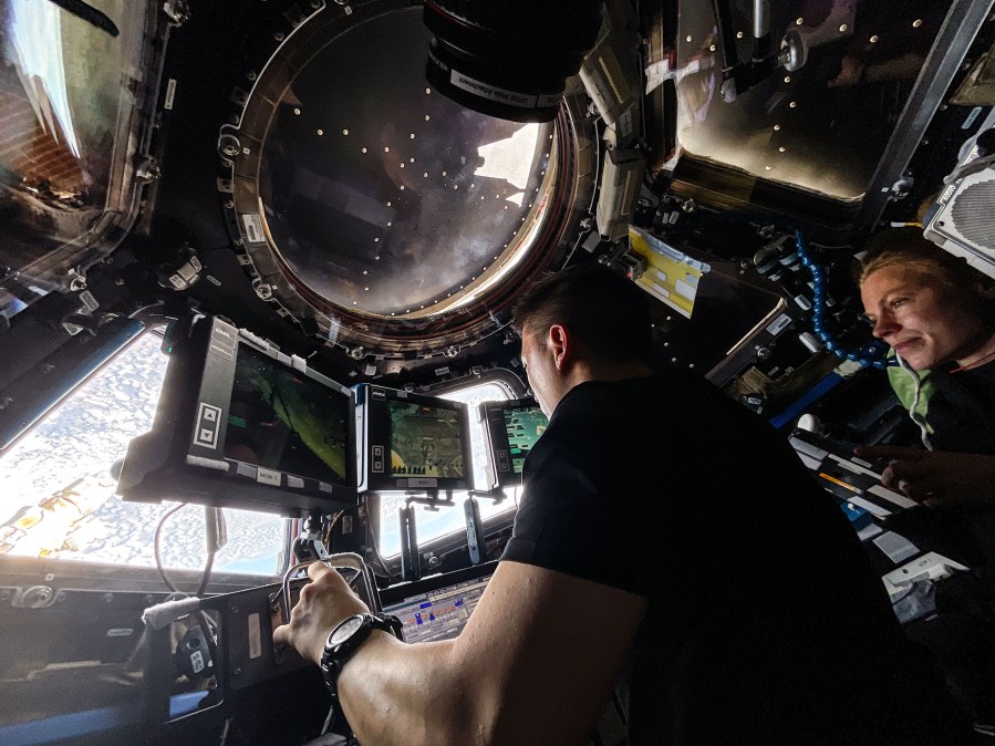 Expedition 73 Flight Engineers Jonny Kim and Zena Cardman, both NASA astronauts, practice Canadarm2 robotic maneuvers at the robotics workstation inside the International Space Station's cupola. The duo was preparing for the robotic capture of the Northrop Grumman Cygnus XL cargo spacecraft that launched on Sept. 14, 2025, and arrived on Sept. 18 delivering about 11,000 pounds of science, supplies, and hardware to the Expedition 73 crew. Credit: NASA