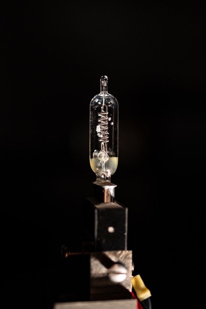 In the middle of the photo is a slender lightbulb with a spiral filament. The entire rest of the photo is black.